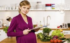 Беременная женщина на кухне рассчитывает рацион дня